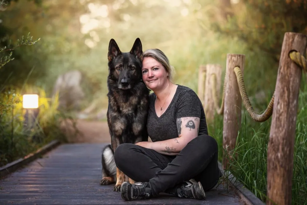 Frau kuschelt sich an Schäferhund im Park